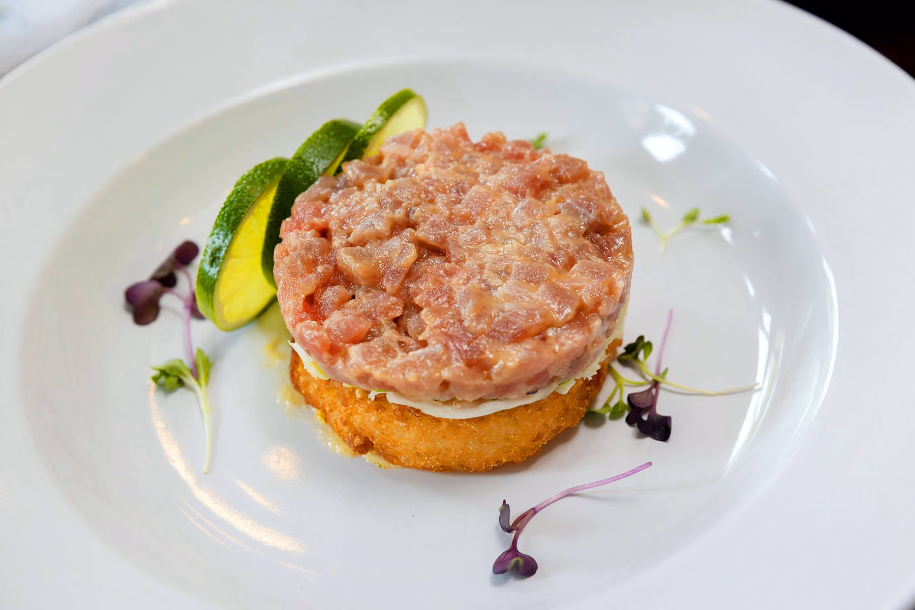 House-made tuna tartare served with fresh avocado, microgreens, and herbs for a light, refreshing seafood appetizer.