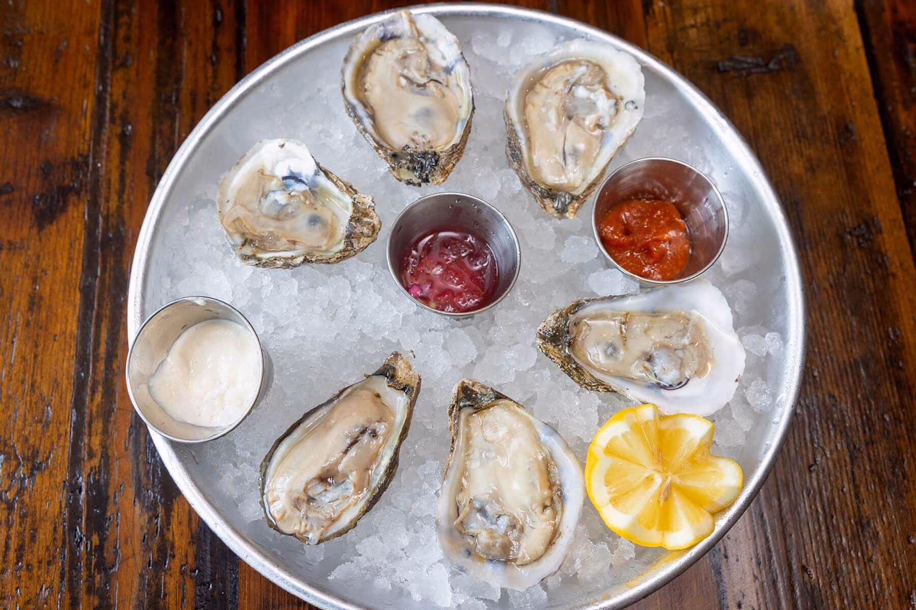 Fresh oysters on the half shell served over ice with cocktail sauce, mignonette, lemon wedges, and horseradish.