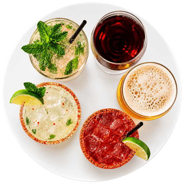 Overhead view of three cocktails, a glass of red wine, and a beer arranged on a white serving plate.